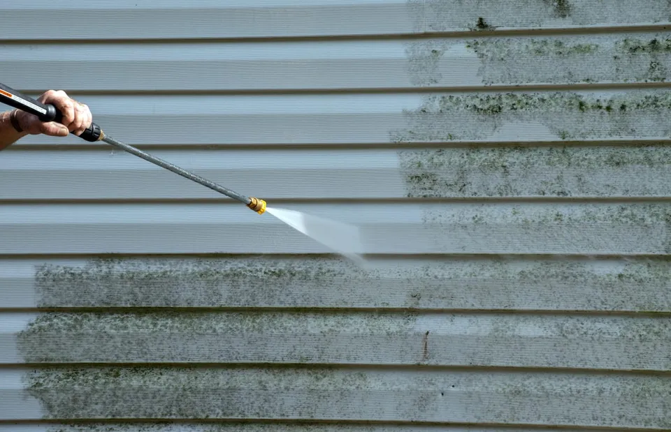 Siding half-washed, showing the clean side against years of grime