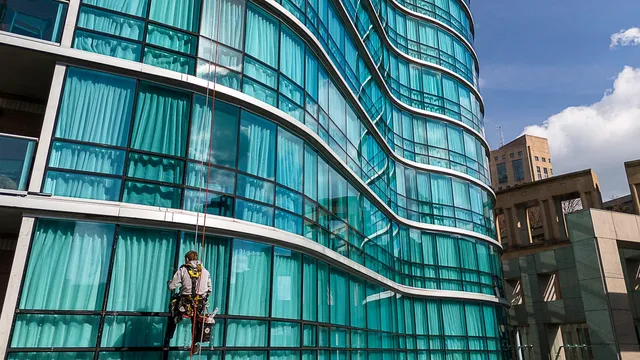 Rope-access technician washing windows on a high-rise glass tower