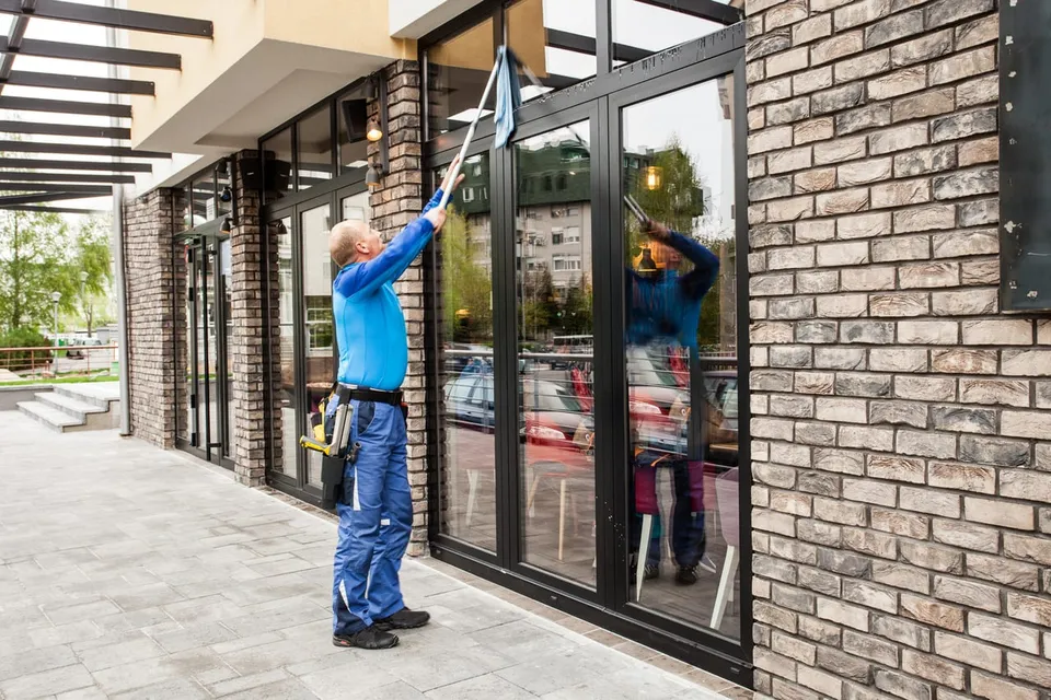 Technician cleaning storefront glass with a pole