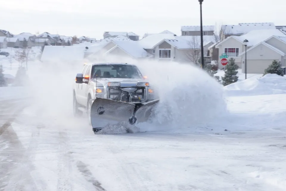 North Shore Snow plow truck clearing a snowy residential street